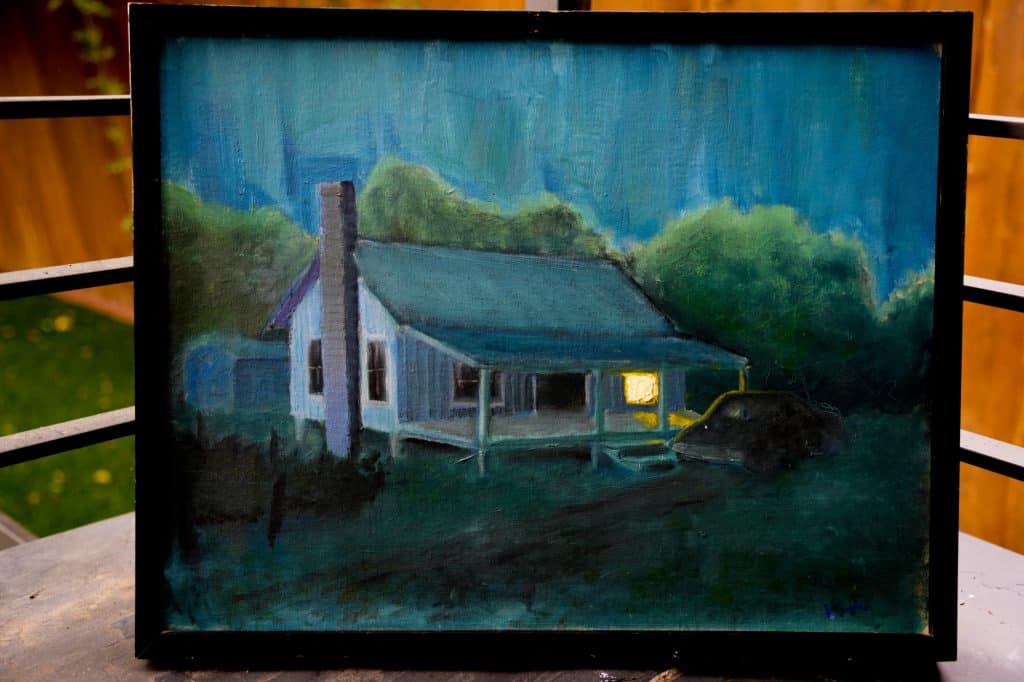 Painting of a small house at night with one window glowing and a car under the porch, framed canvas