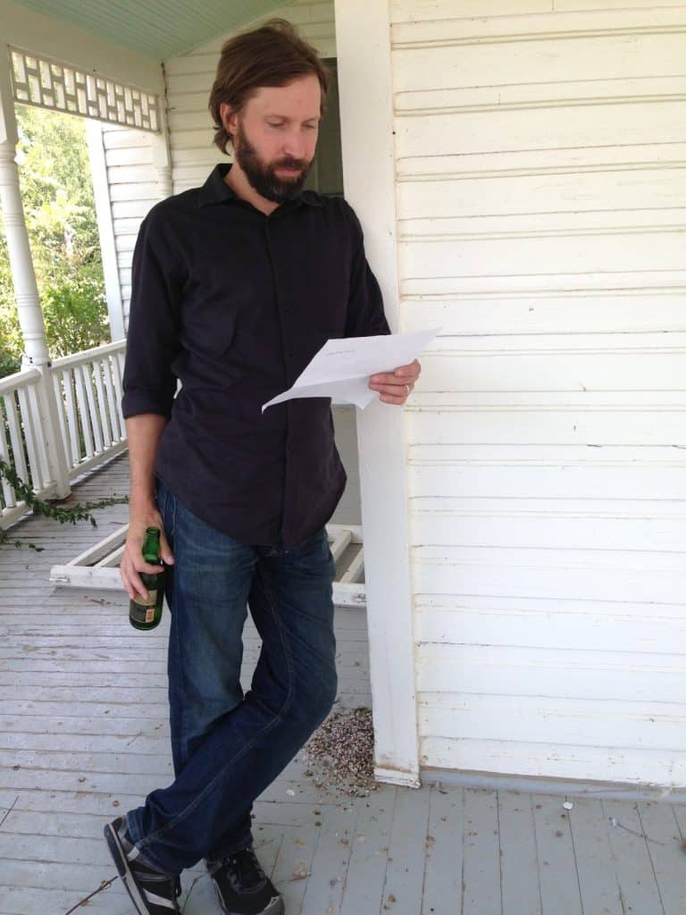 Owen Temple reading a lyric sheet on the porch